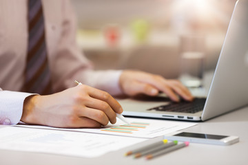 Fototapeta premium Business Person reading Data on paper Charts and Computer