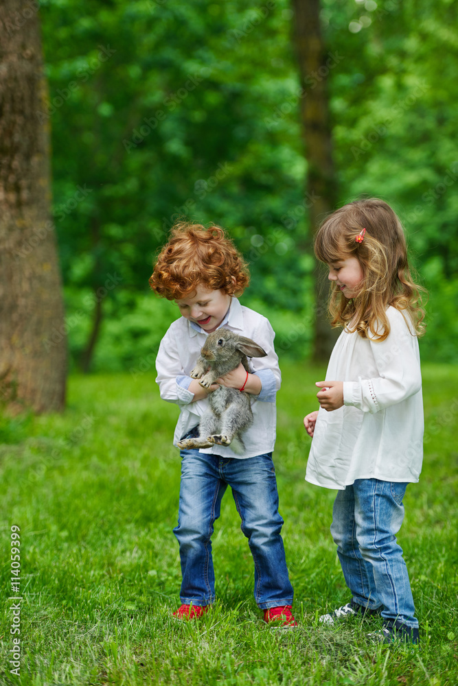 Wall mural boy and girl playing with rabbit