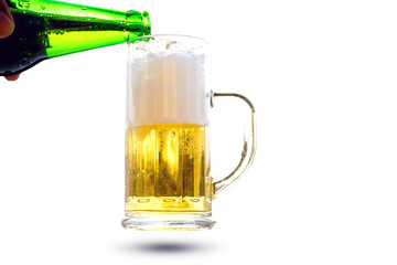 Pour beer from a bottle into a glass with a handle isolated on white background.