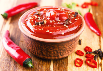 Red hot chilli sauce on wooden background
