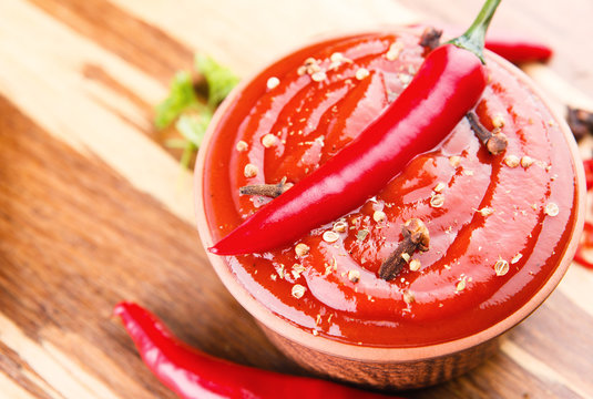 Red hot chilli sauce on wooden background
