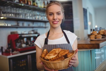 Portrait of confident waitress serving breads at coffee house