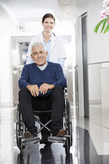 Female Doctor Pushing Senior Patient In Wheel Chair