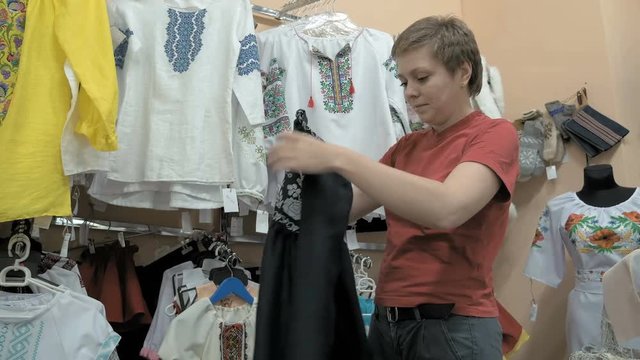 A customer trying to find the perfect blouse. Store contains various selections of colors and fabrics to choose from. Fashionable yet comfortable is key. 4K UHD video footage.