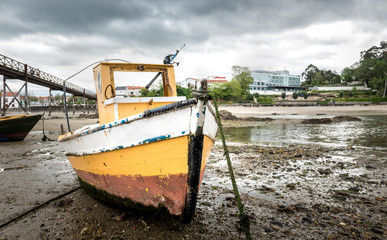 Old fishing boat is moored on beach at low tide.