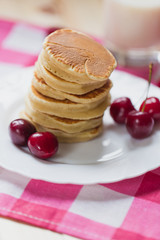 Tasty Pancake with fresh cherries on a white plate. American breakfast