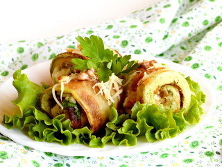 Fried zucchini rolls with cheese, fresh parsley and walnuts. Zucchini rolls on a green lettuce and on a plate. Festive vegetable appetizer. Closeup