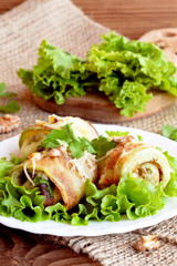 Fried zucchini rolls with cheese, walnuts and herbs. Fried stuffed zucchini rolls on a plate. Fresh lettuce leaves on a wooden board. Healthy and delicious summer appetizer