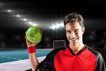 Composite image of portrait of happy athlete man holding a ball 