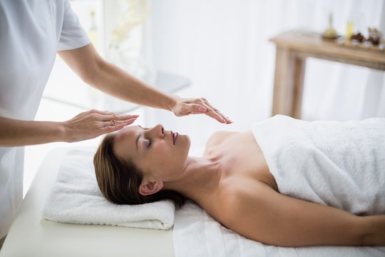 Midsection of therapist performing reiki on woman