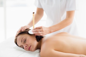 Fototapeta na wymiar Woman receiving ear candle treatment from masseur