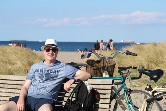 Old man on the beach in Copenhagen with hat and bicycle 