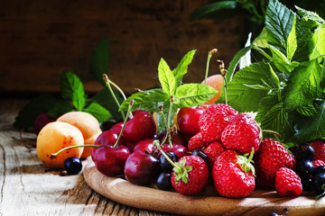 Ripe tasty summer fruits and berries with leaves on the old wood