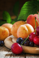 Ripe tasty summer fruits and berries with leaves on the old wood