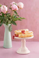 Eclairs with buttercream filling on a pink cake stand