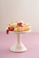 Eclairs with buttercream filling on a pink cake stand
