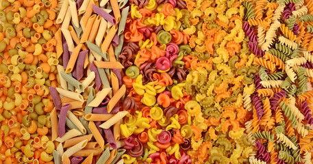 Assortment of colored uncooked Italian pasta as background