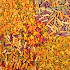 Assortment of colored uncooked Italian pasta as background