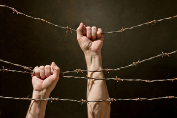 hand behind barbed wire