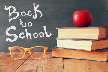 Back to school concept. Blackboard with books, apple and glasses
