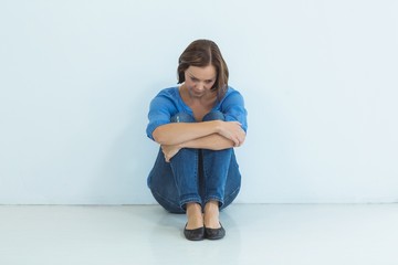 Sad woman sitting against wall
