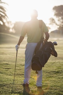 Full length Rear view of man carrying golf bag 