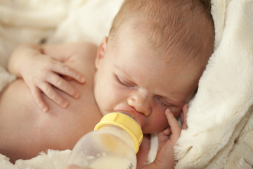 Baby drinking from bottle with nipple in mouth