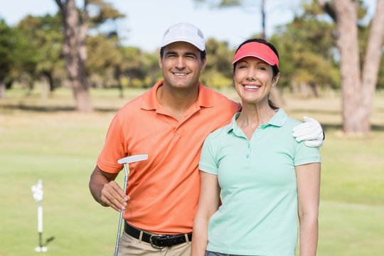 Portrait of smiling golfer couple with arm around 