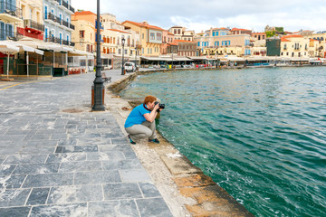 The woman with the camera on the waterfront of Chania.