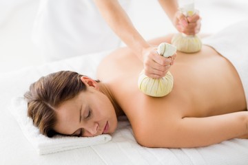 Obraz na płótnie Canvas Woman receiving herbal compress massage from masseur