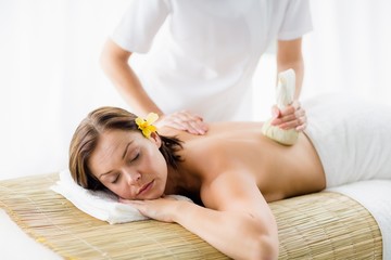 Obraz na płótnie Canvas Masseur giving herbal compress massage to woman