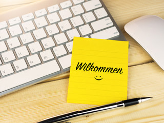 Wilkommen or welcome in german on sticky note on desk