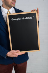 Man in a suit with a black board in his hands on a white backgro
