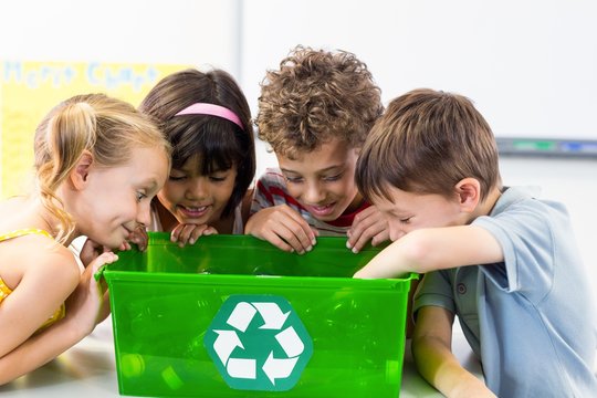Children looking at plastic bottles in recycling box - Powered by Adobe