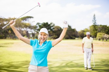 Portrait of cheerful golfer woman with arms raised 