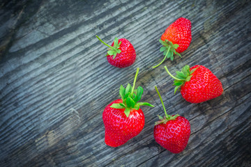 Strawberries with green leaves on a textured board