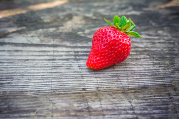 Strawberries with green leaves on a textured board