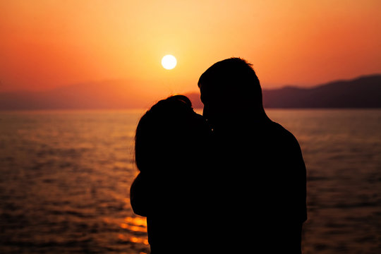 Young Couple Enjoying the Sunset on the Beach. Kiss. Silhouette