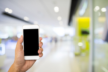 Hand hold blank smartphone on blur supermarket background