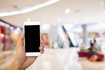 Hand hold blank smartphone on blur supermarket background
