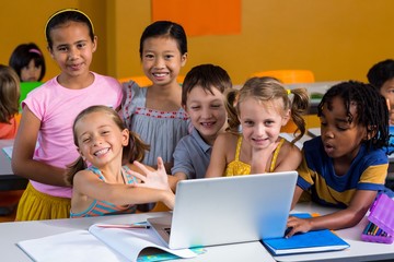 Smiling multi ethnic children using laptop