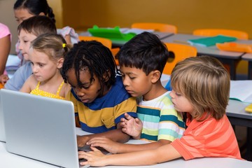 Multi ethnic classmates using laptop