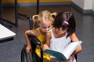 Girls sitting on wheelchair reading book