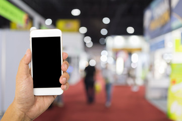 Hand hold smartphone on blur exhibition background