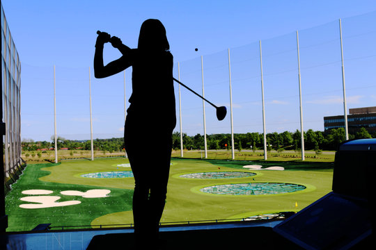 Silhouette of Girl Swinging Golf Club with Shadow on Driving Range at Sunset