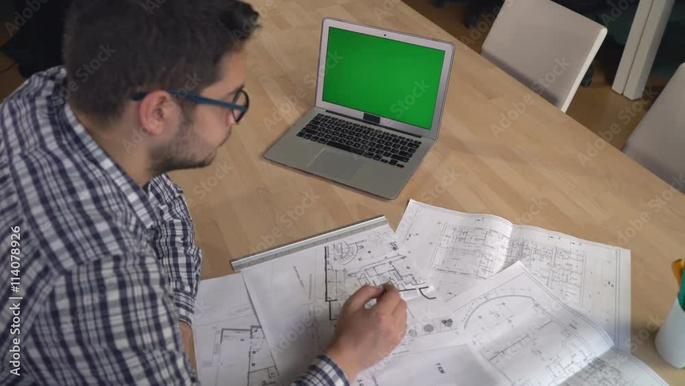 Poster young professional designer checking architectural sketch at the working place with laptop pencil li