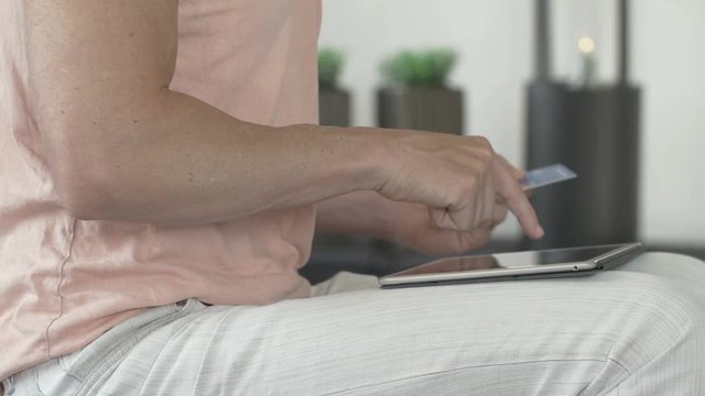 Man online shopping on his tablet computer and pay with a credit card.