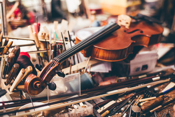 Close up of violin, luthier workshop in background - obrazy, fototapety, plakaty