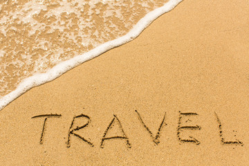 Fototapeta premium Travel - word drawn on the sand beach with the soft wave.