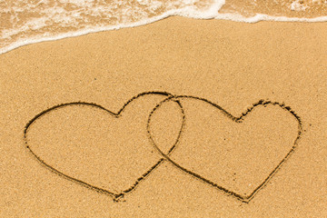 Two hearts drawn on the beach sand.